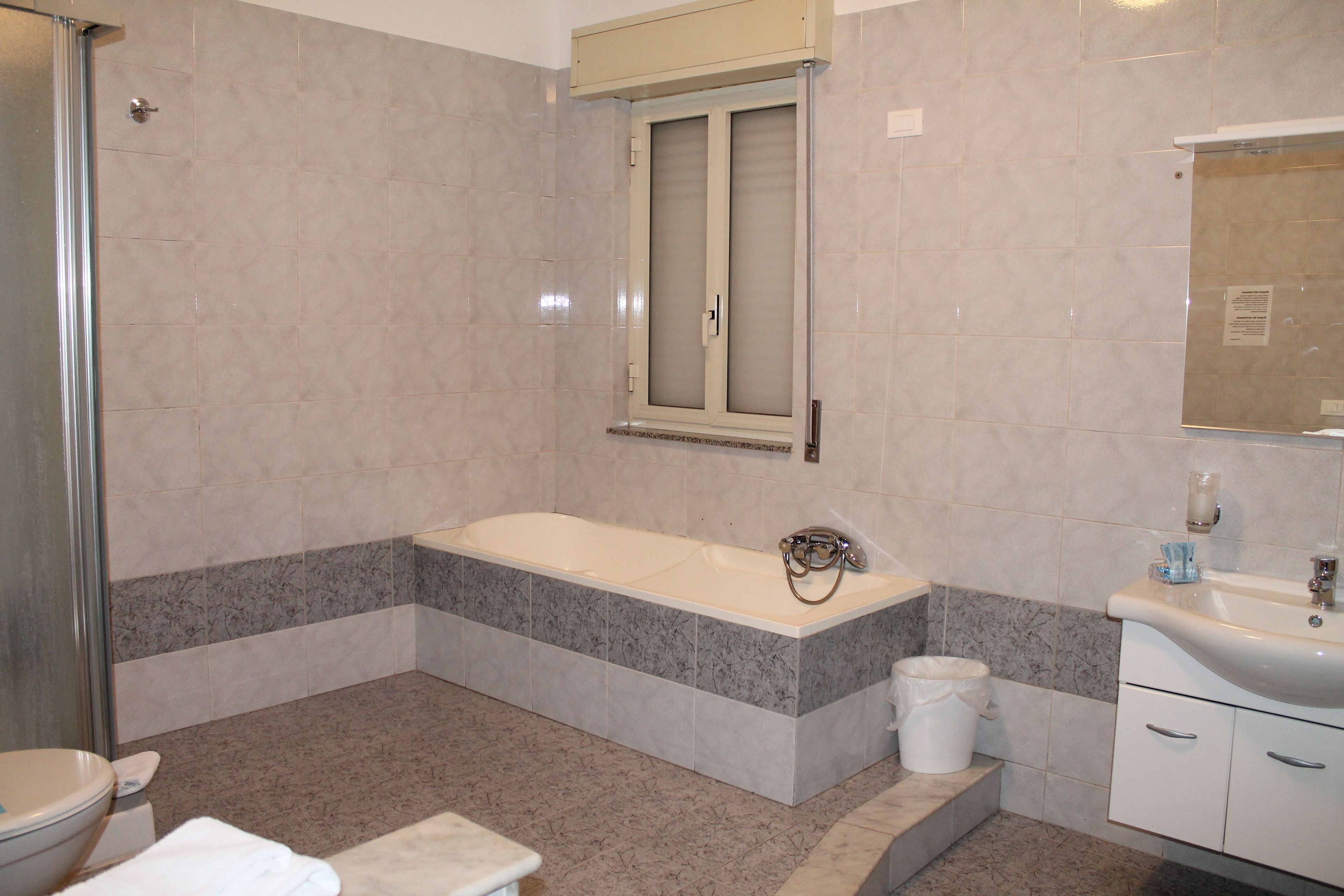 A bathroom with a bathtub, toilet, sink, and a shower area.