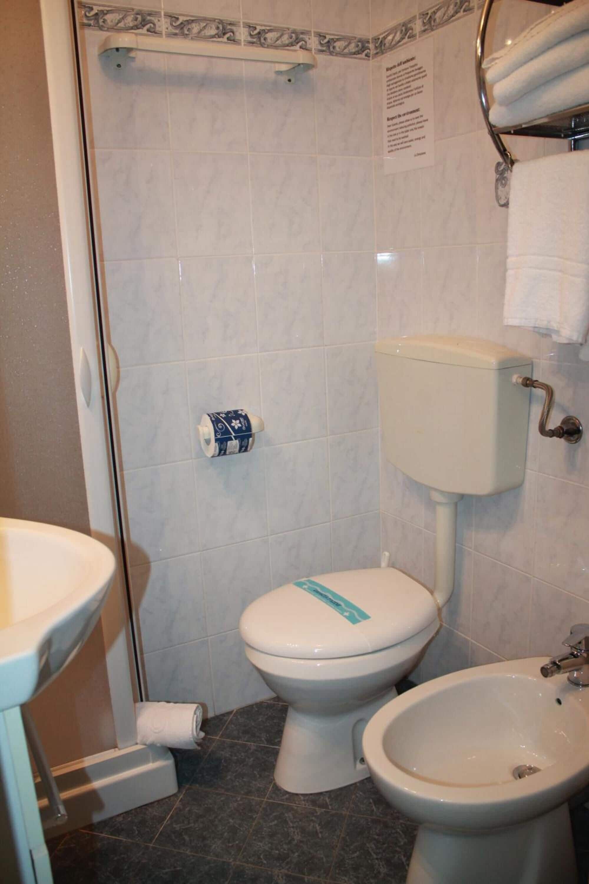Une salle de bain équipée de toilettes, d’un bidet et d’un porte-serviettes.