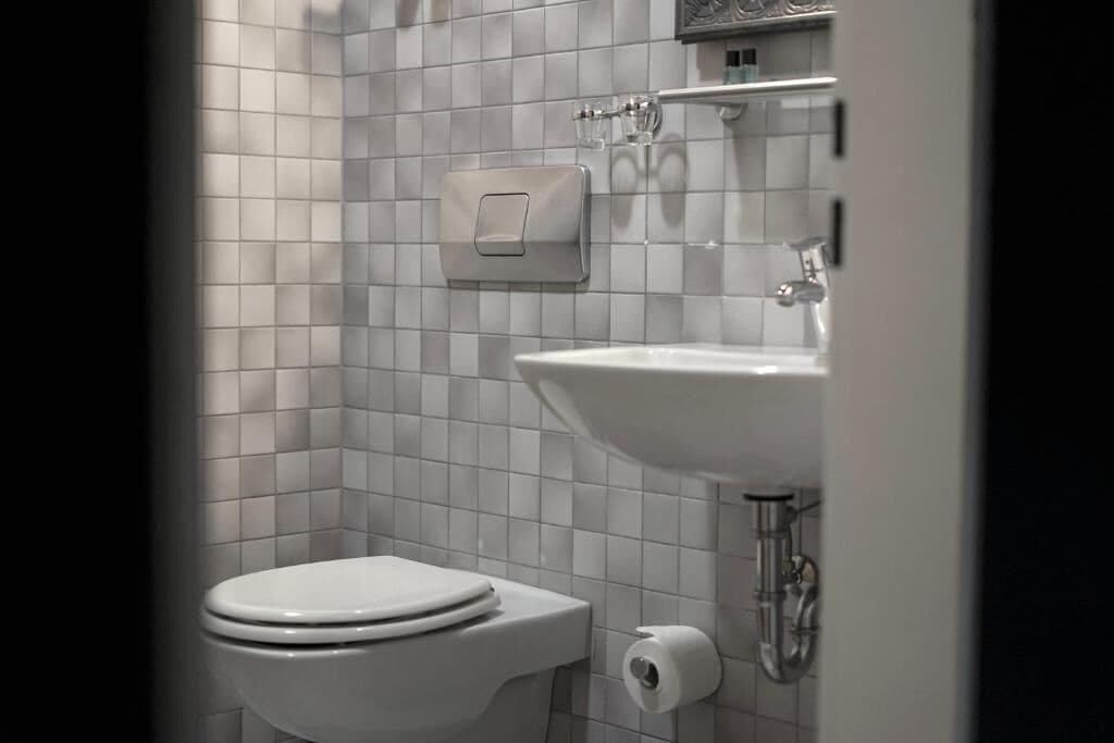 A bathroom with a toilet, a sink, and a paper towel dispenser.
