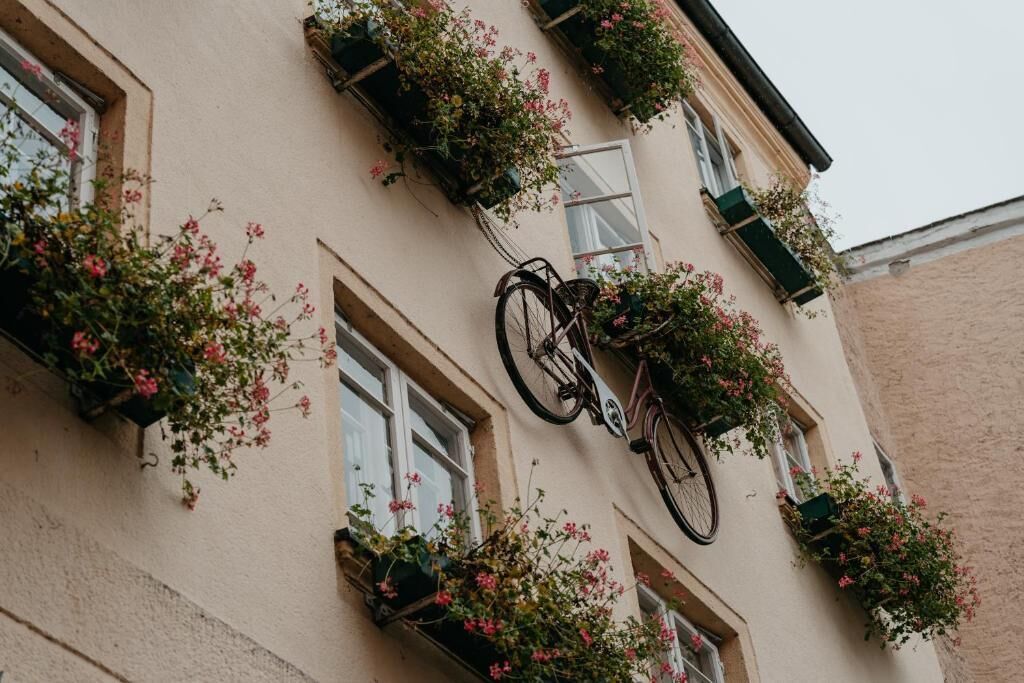 A building with multiple windows, some with flower boxes and a bicycle leaning against the wall.