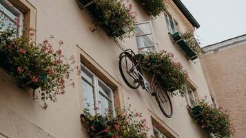A building with multiple windows, some with flower boxes and a bicycle leaning against the wall.