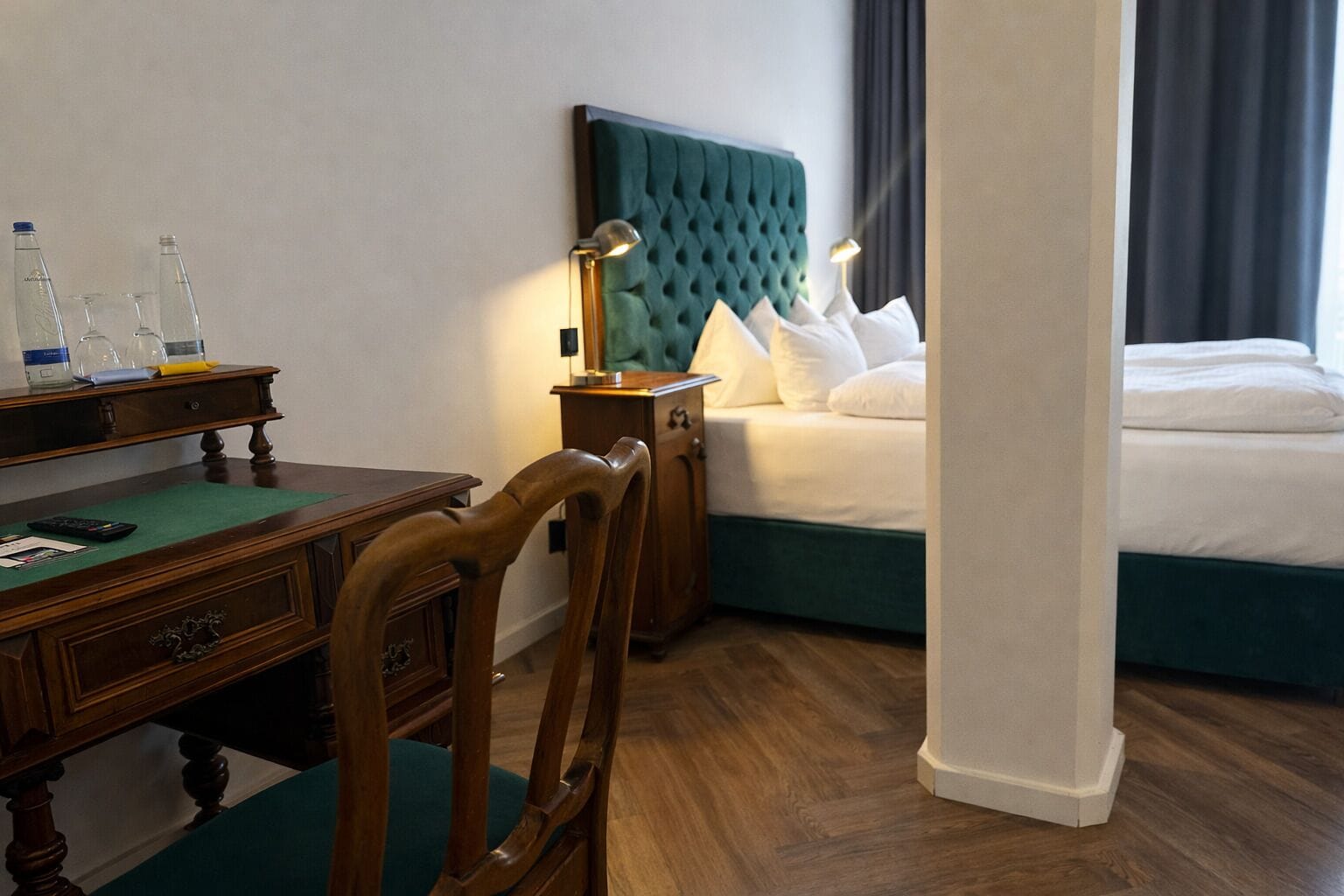 Ein Hotelzimmer mit Bett, Schreibtisch, Stuhl, Nachttisch und Lampe.
