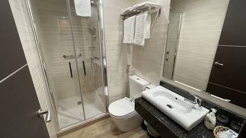Un baño moderno con ducha de vidrio, inodoro y lavabo con espejo.