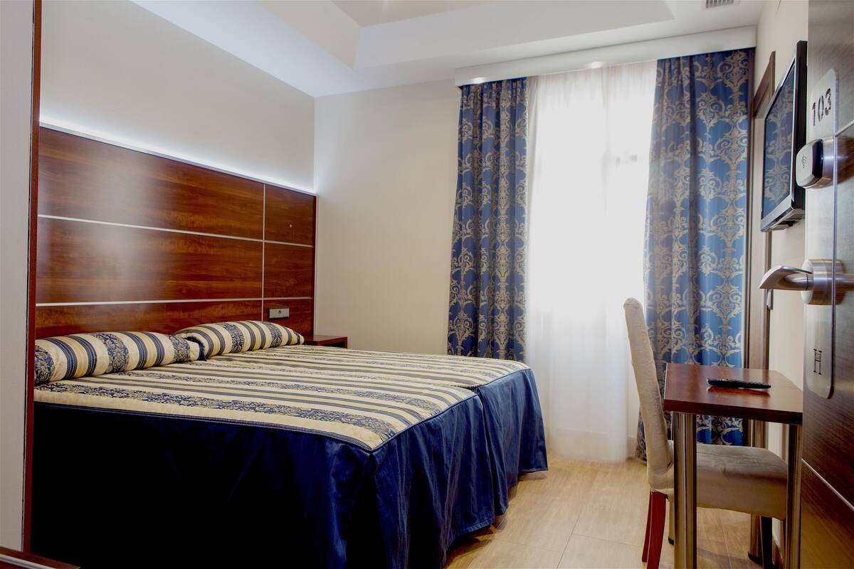 A hotel room with a bed, a desk, and a TV.