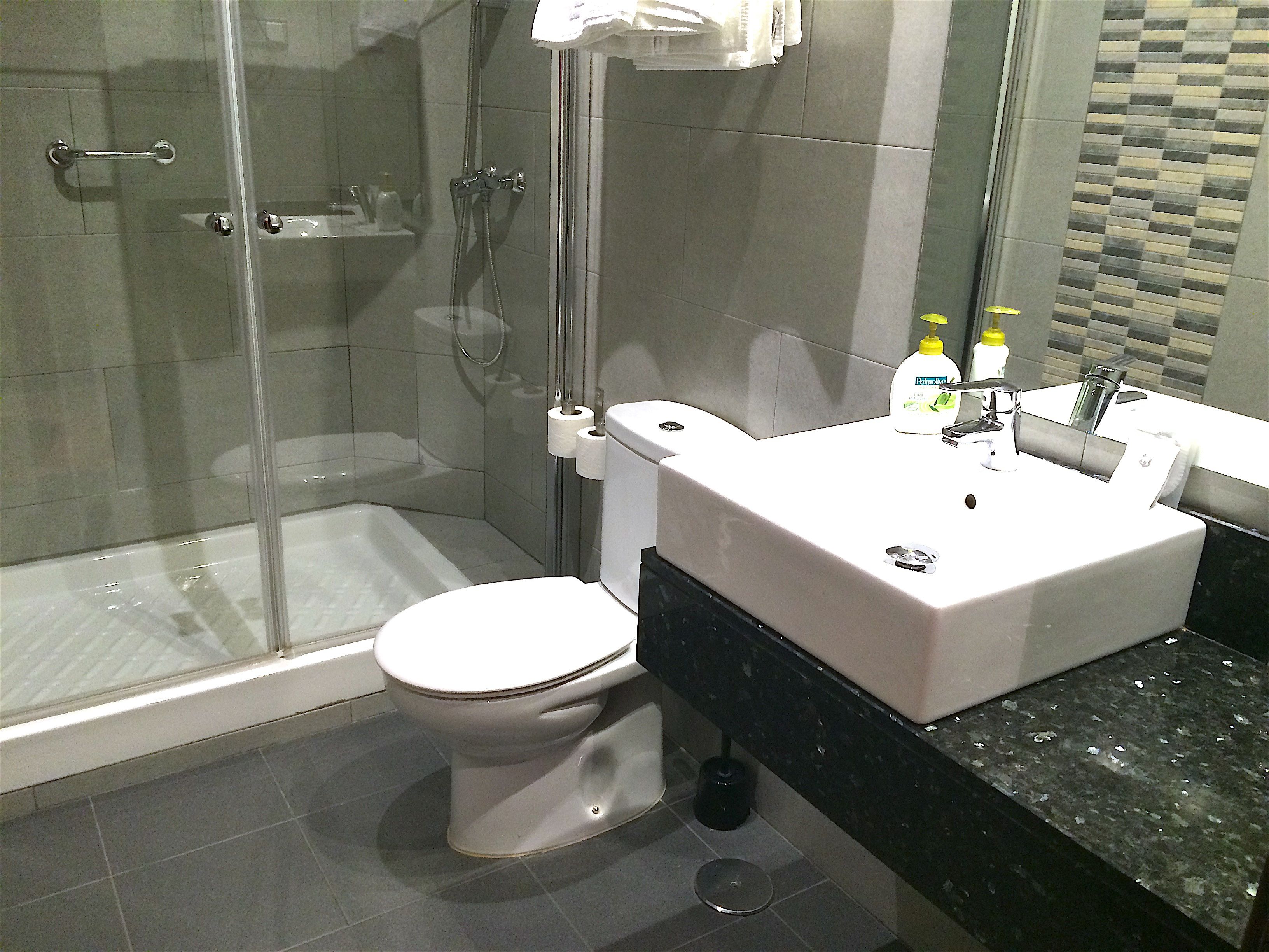 Ein modernes Badezimmer mit Duschkabine aus Glas, einer weißen Toilette und einem Waschbecken mit schwarzer Arbeitsplatte.