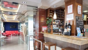 Zona de bar moderna con mostrador, taburetes y una variedad de botellas.