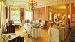 A dining area with multiple tables set for service, a chandelier, and classical decor. - Hotel Le Manoir (Barr)