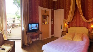 A hotel room with a bed, a television, a chair, and a balcony with outdoor furniture. - Hotel Le Manoir (Barr)