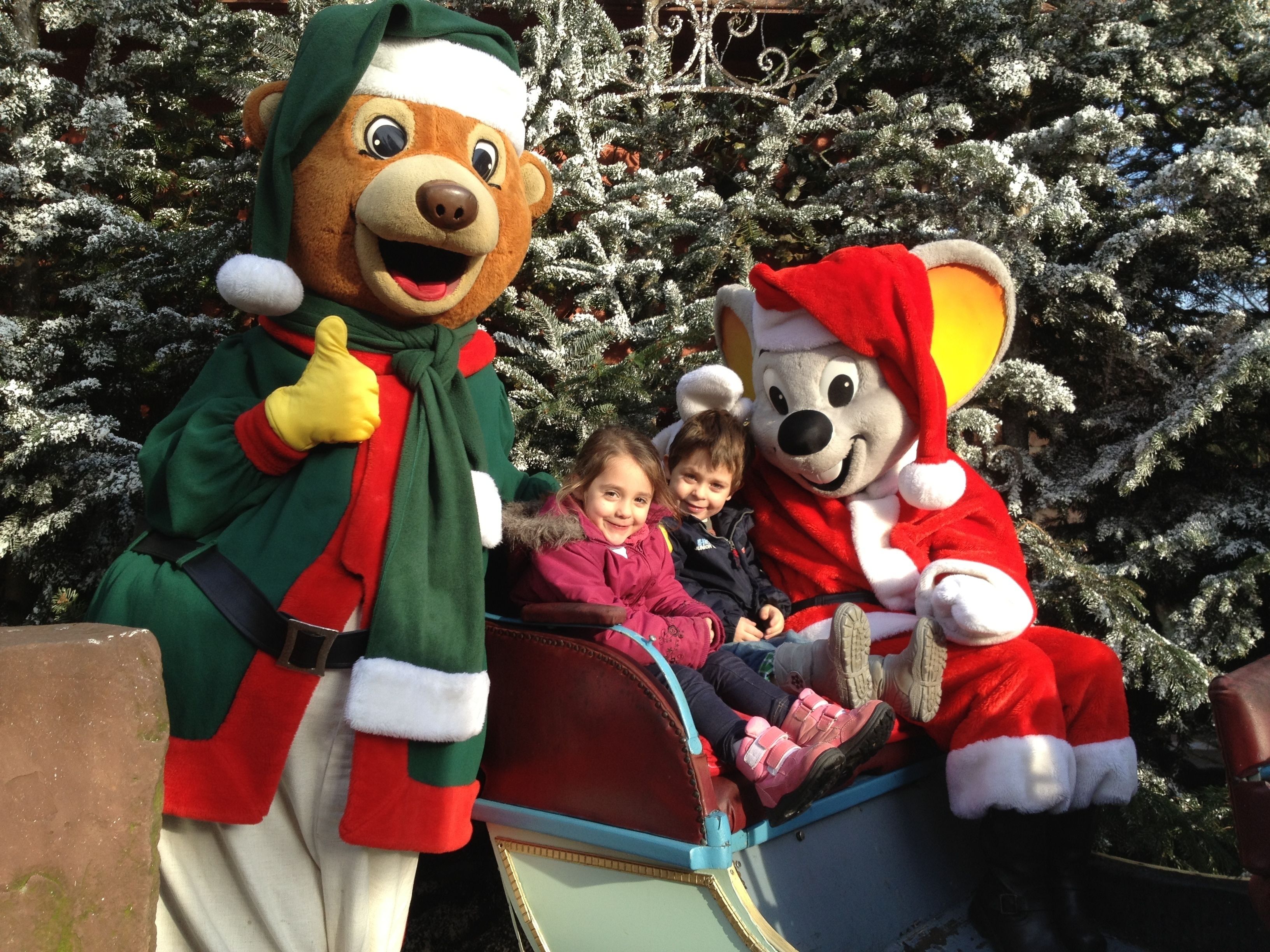 Une personne déguisée en Père Noël, accompagnée d’un enfant et d’un autre enfant dans un traîneau.