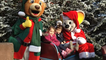 Une personne déguisée en Père Noël, accompagnée d’un enfant et d’un autre enfant dans un traîneau.