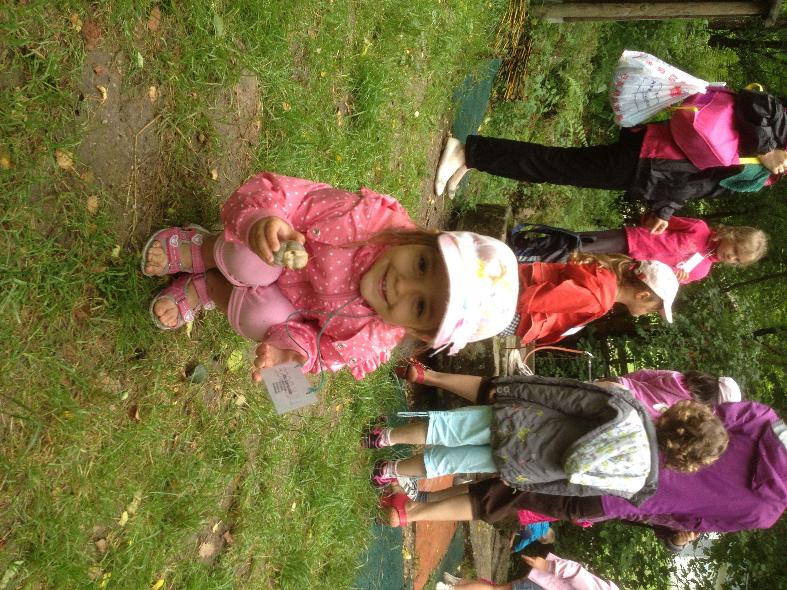 Un groupe d’enfants assis sur l’herbe, dont certains tiennent des feuilles de papier.
