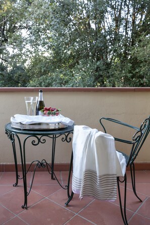 A table with a bottle, glasses, and strawberries on a balcony with a chair and a white cloth. - Hotel Franceschi (Forte dei Marmi)