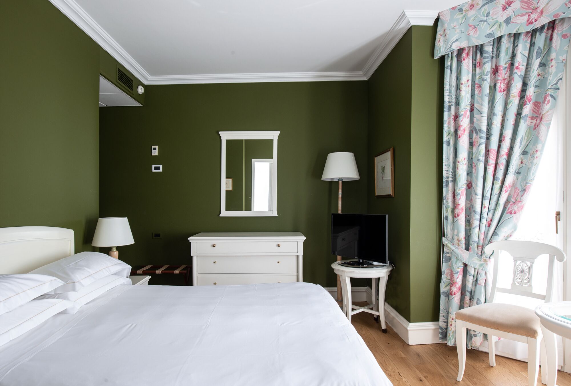A bedroom with a bed, a dresser, a television, and a chair.