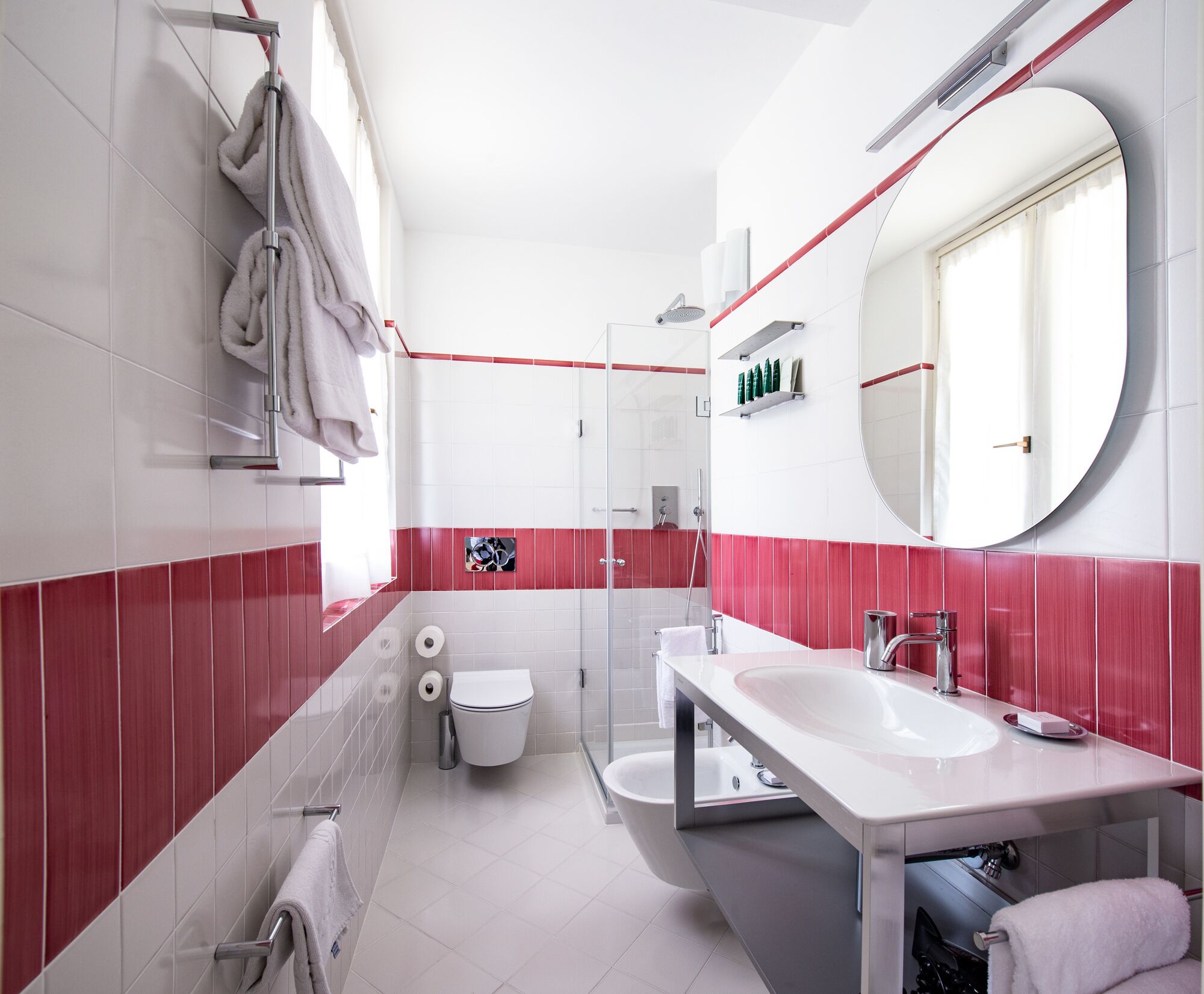 Un baño moderno con un lavamanos blanco, una cabina de ducha de vidrio y un espejo grande.
