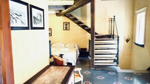 A bedroom with a bed, a wooden bench, a staircase, and a wall with framed pictures. - Antica Dimora San Girolamo (Licata)