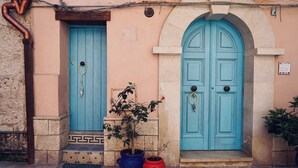 A building with two turquoise doors, a potted plant, and a small sign on the wall. - Antica Dimora San Girolamo (Licata)
