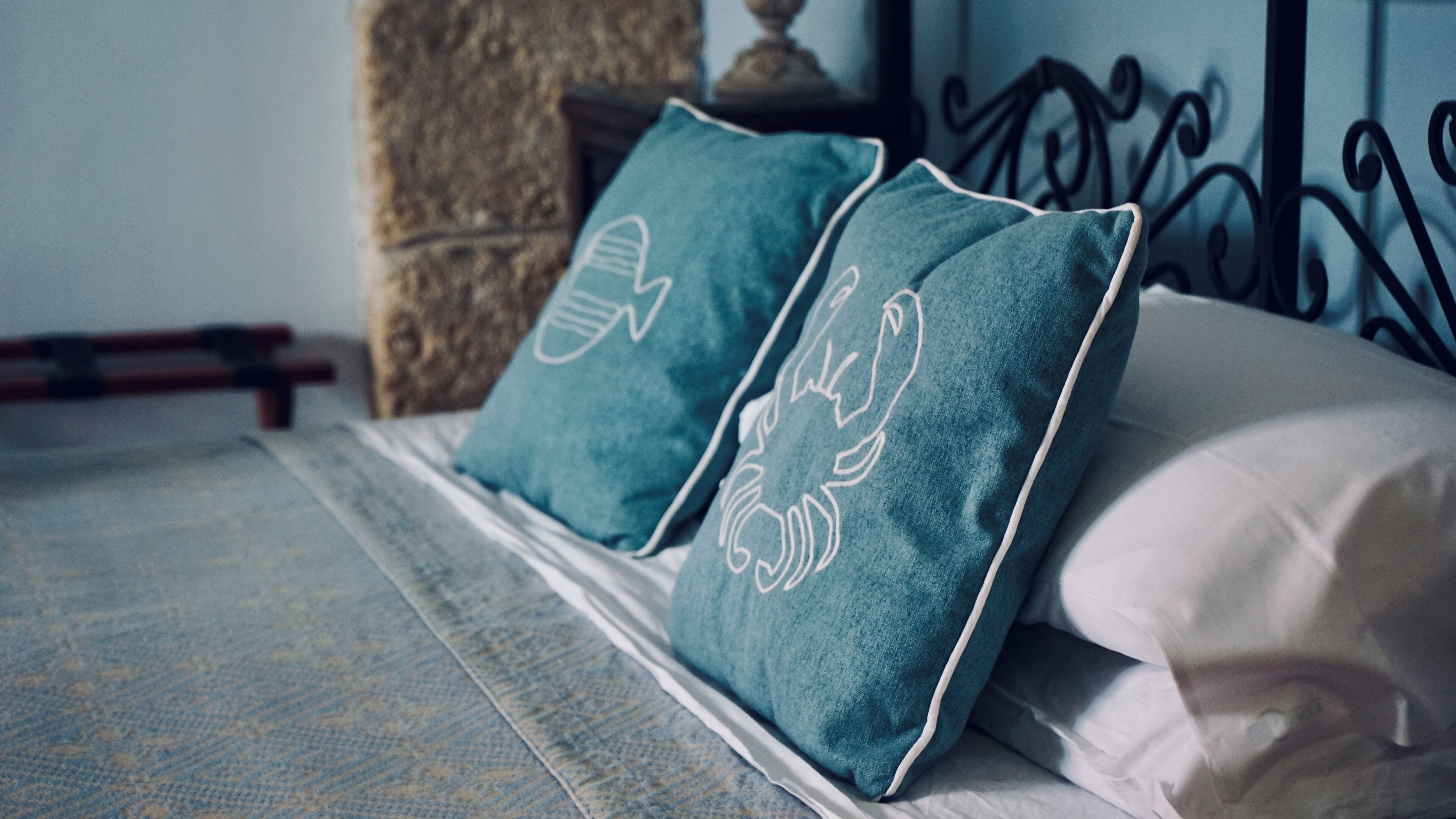 Cama com dois travesseiros verde-água e um travesseiro branco.