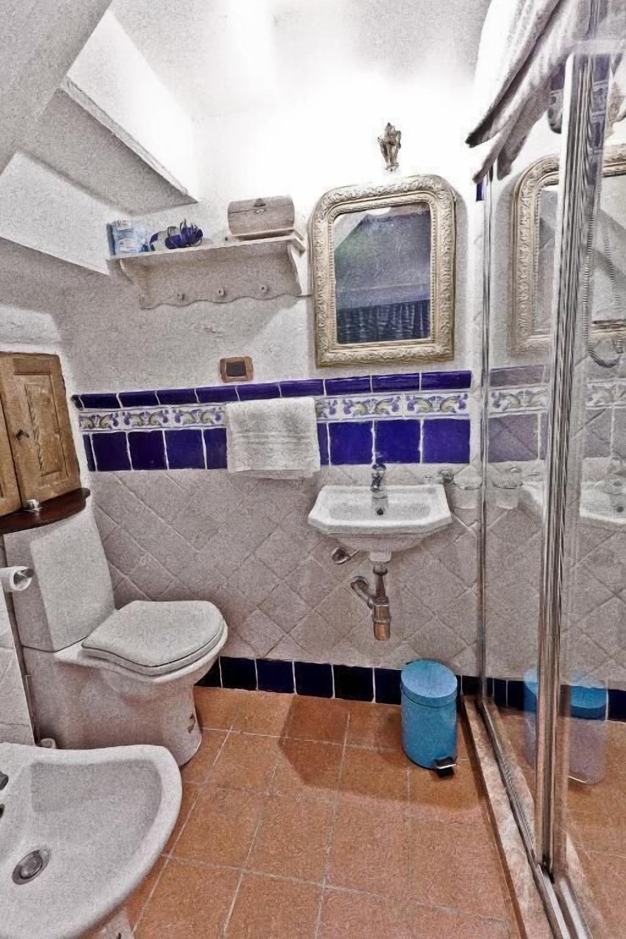 A bathroom with a toilet, bidet, sink, and a shower area.