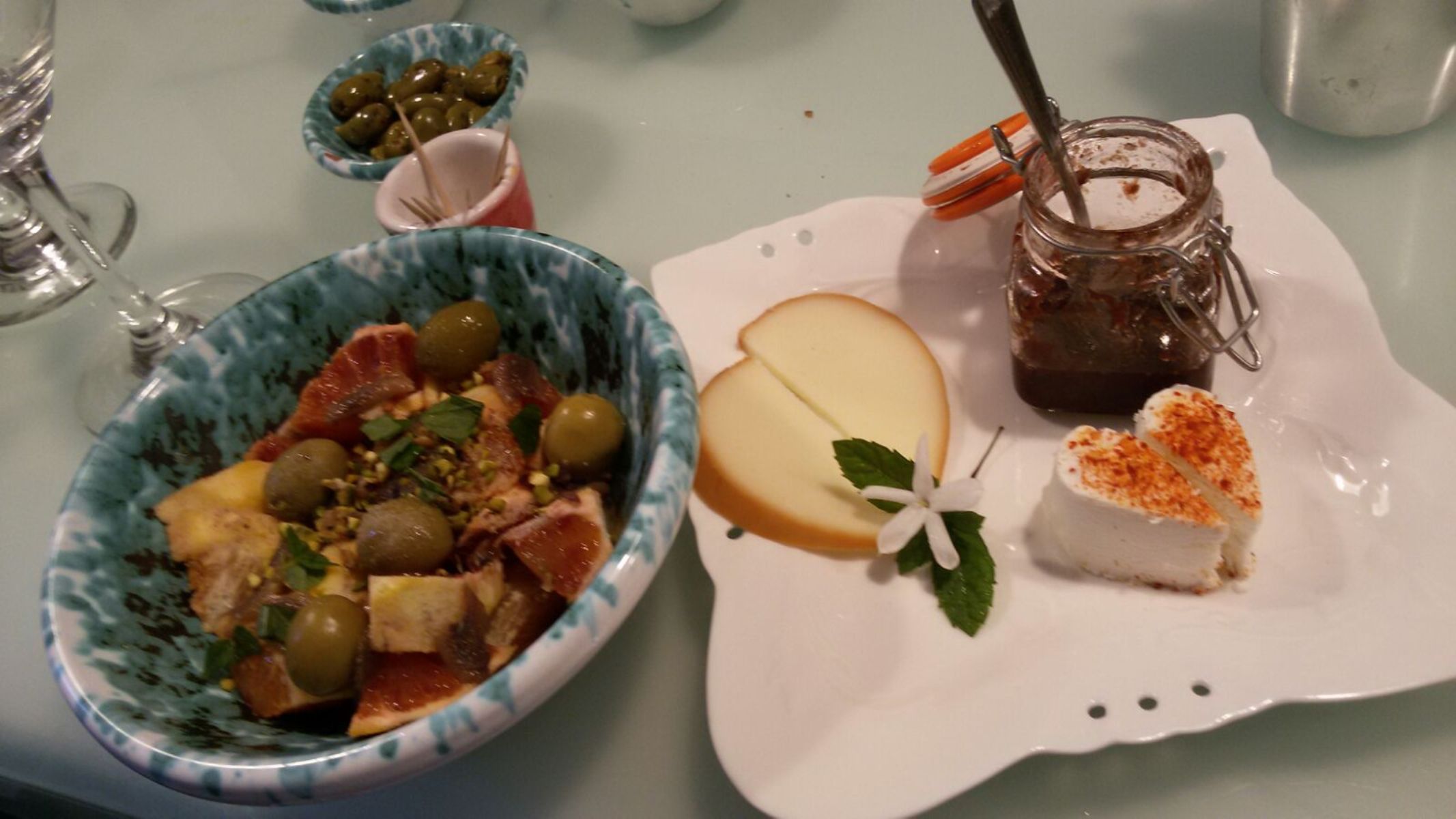 A table with a bowl of salad, a plate with a slice of cake, and a jar of jam.