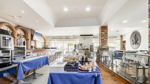 A buffet setup with various food items and a television screen. - Residencial Marés (Tavira)