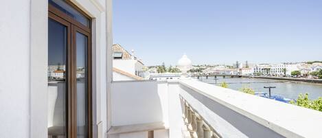 A balcony with a view of a river and a white building with a dome in the distance.