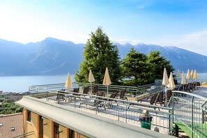 Una terraza con mobiliario exterior y vistas a montañas y un lago.