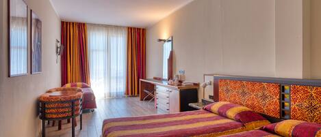 A hotel room with a large bed, a desk, a chair, and a wardrobe.