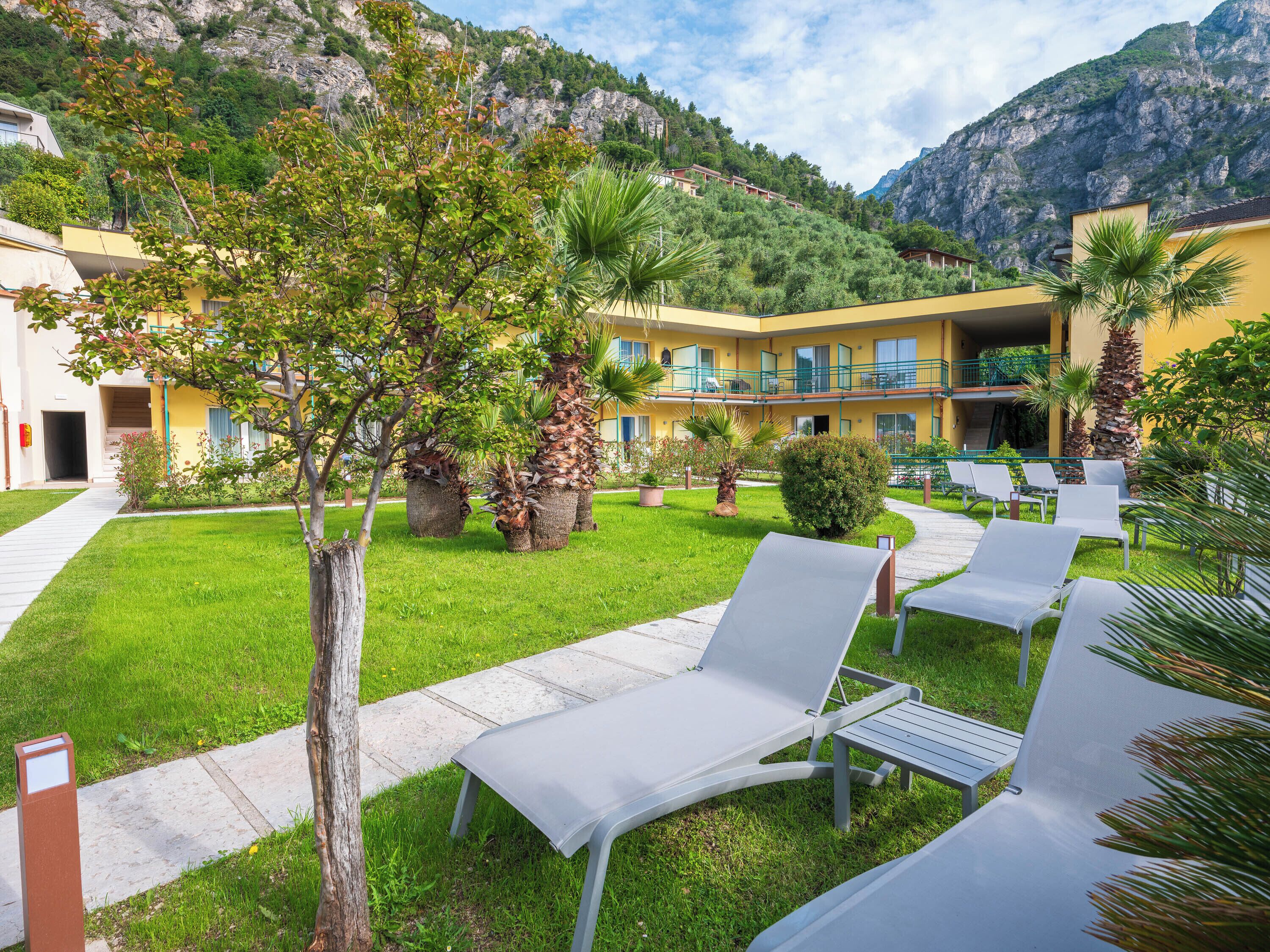 Un patio de hotel con mobiliario exterior, piscina y vistas a las montañas.