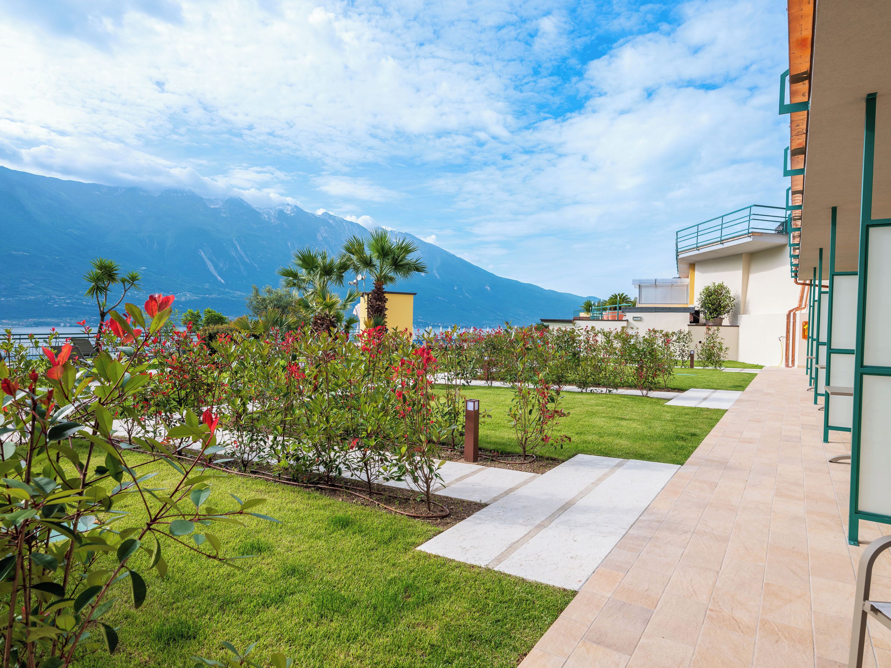 A landscaped outdoor area with a pathway, greenery, and a mountain view.