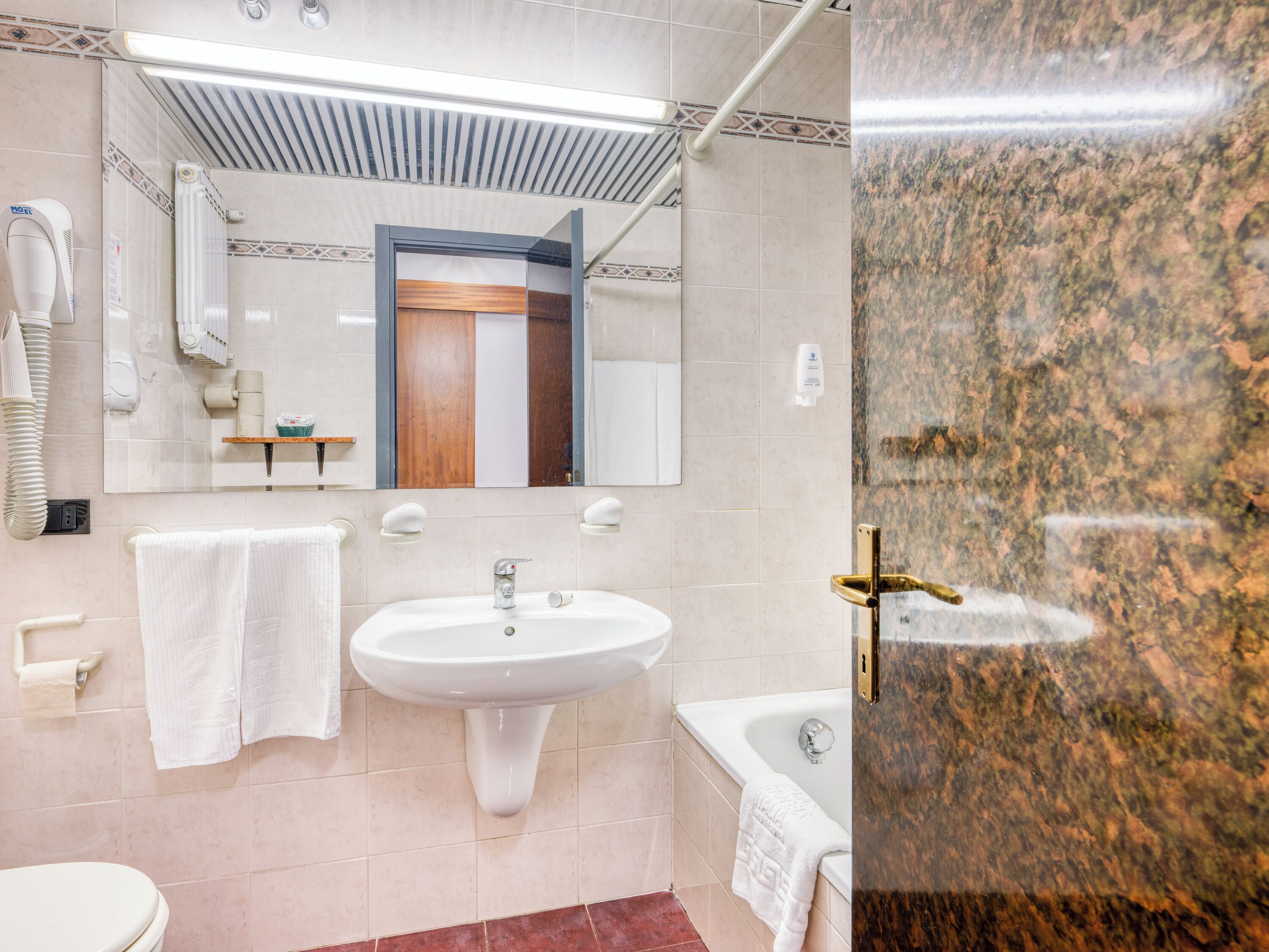 Un baño moderno con lavamanos, espejo, toallero y bañera.