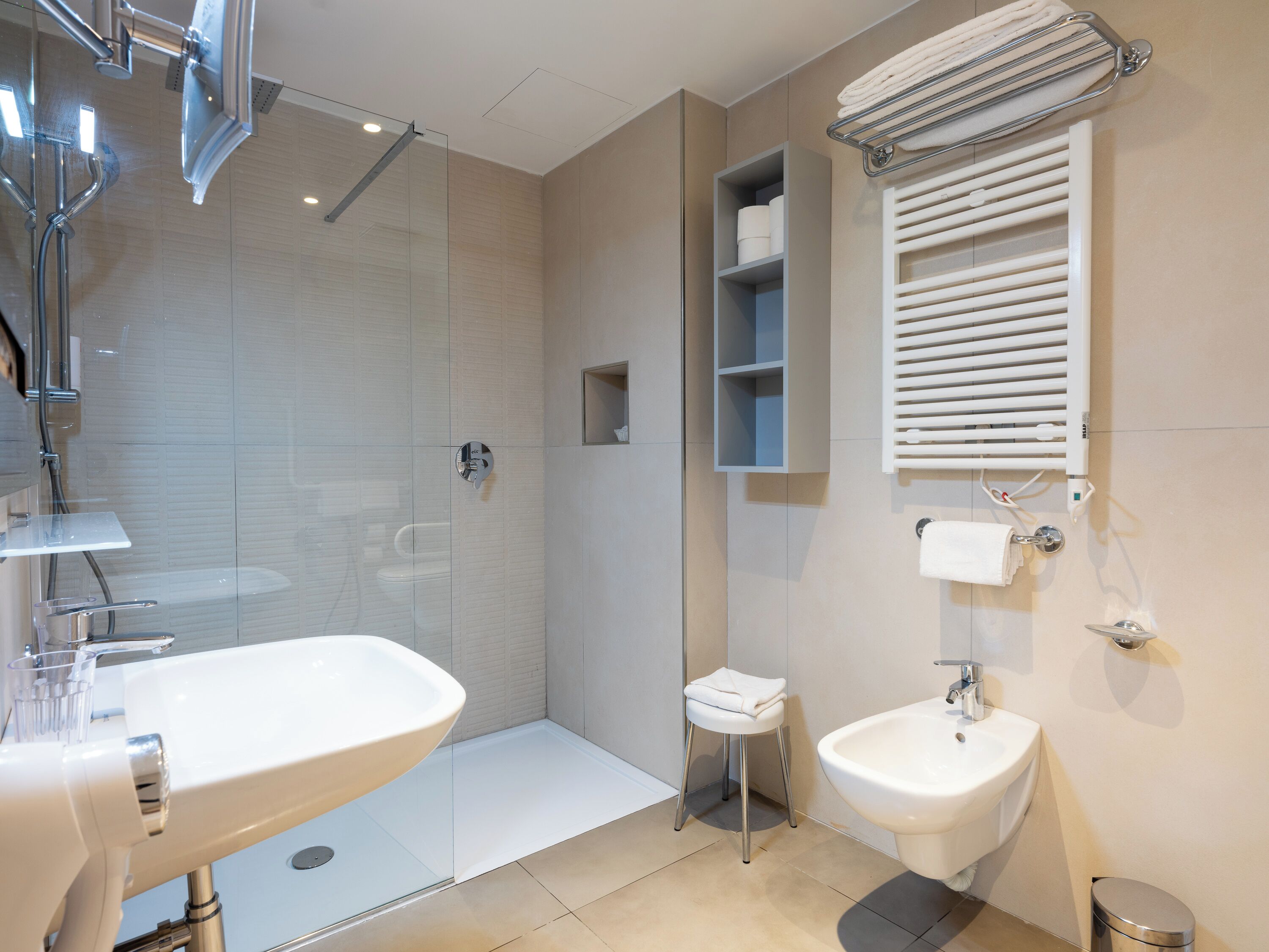 A modern bathroom with a glass-enclosed shower, a double sink, and a towel rack.