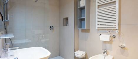 A modern bathroom with a glass-enclosed shower, a double sink, and a towel rack.