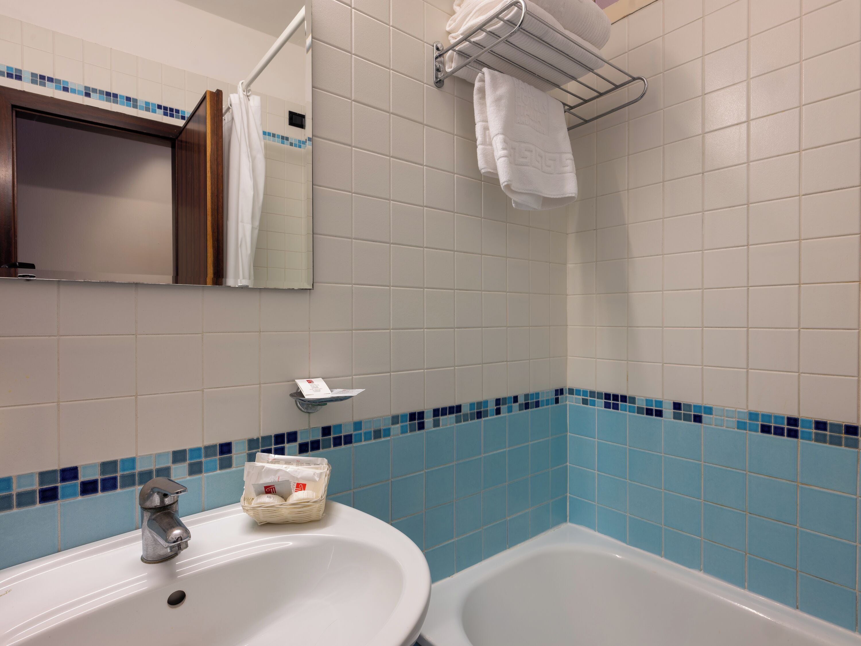 A bathroom with a white sink, a mirror, a towel rack, and a bathtub.