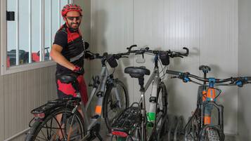 A person standing next to a bicycle in a room with white walls and a window.