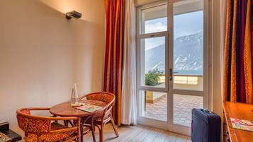Una habitación con una mesa y sillas de madera, una maleta y vistas a montañas a través de un ventanal grande.