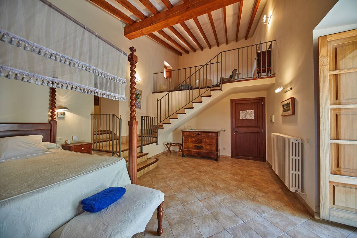 Ein Schlafzimmer mit einem großen Bett, einer Holztreppe, einem Schminktisch und einer Heizung.
