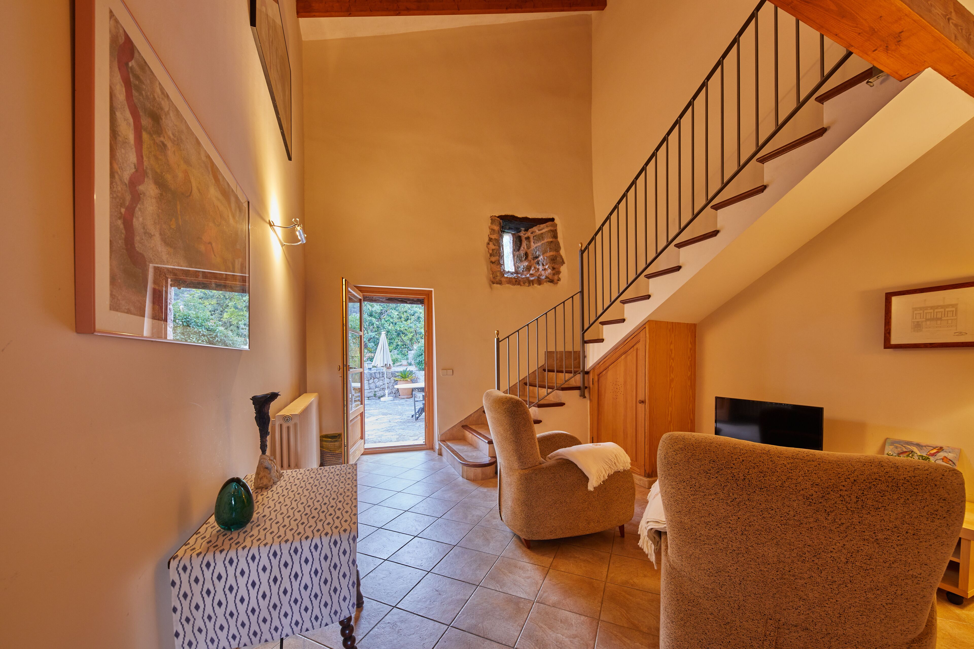 Un vaste salon doté d’un haut plafond, d’un escalier et offrant une vue sur l’extérieur.