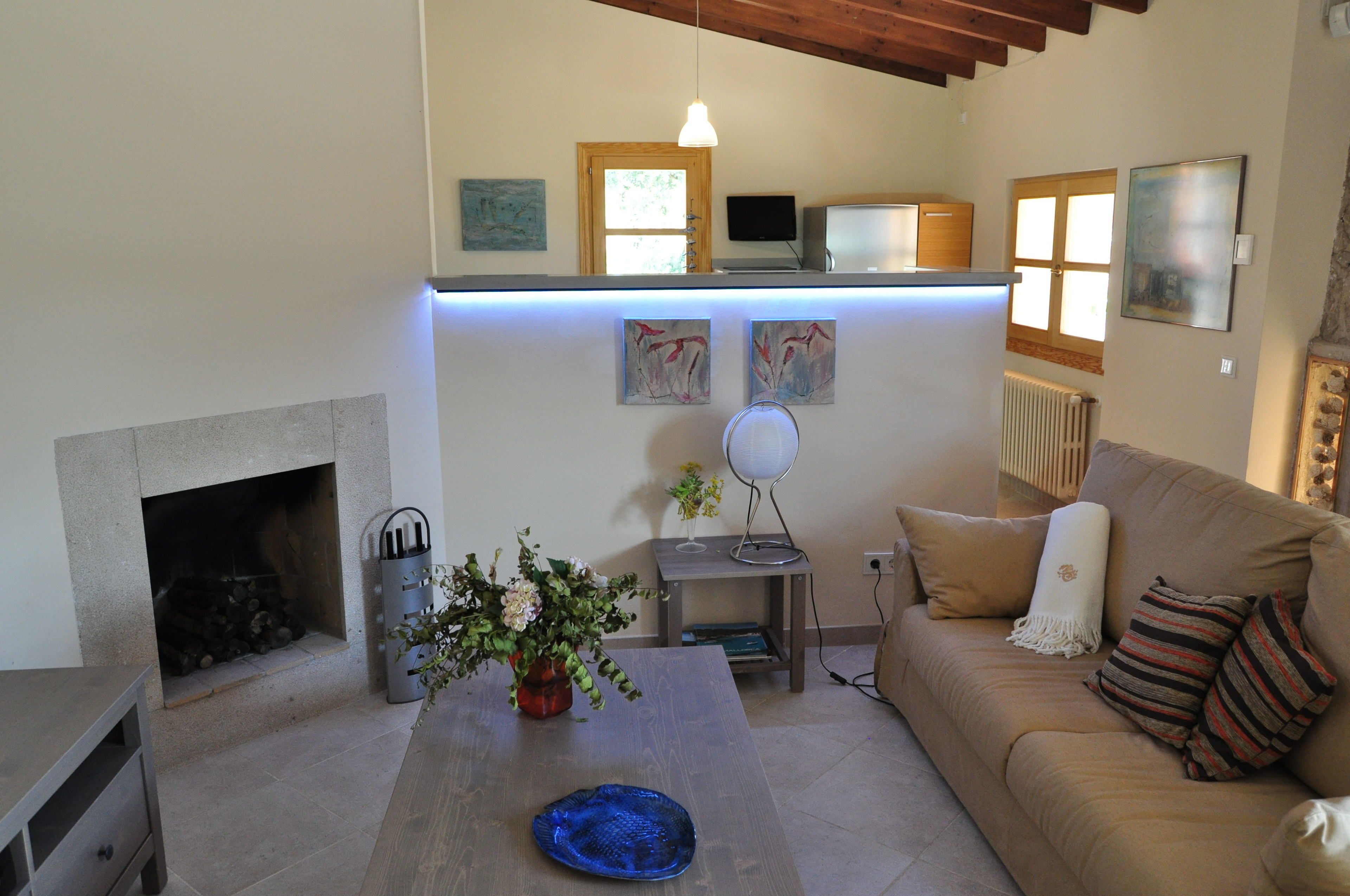 A living room with a fireplace, a sofa, a coffee table, and artwork on the walls.