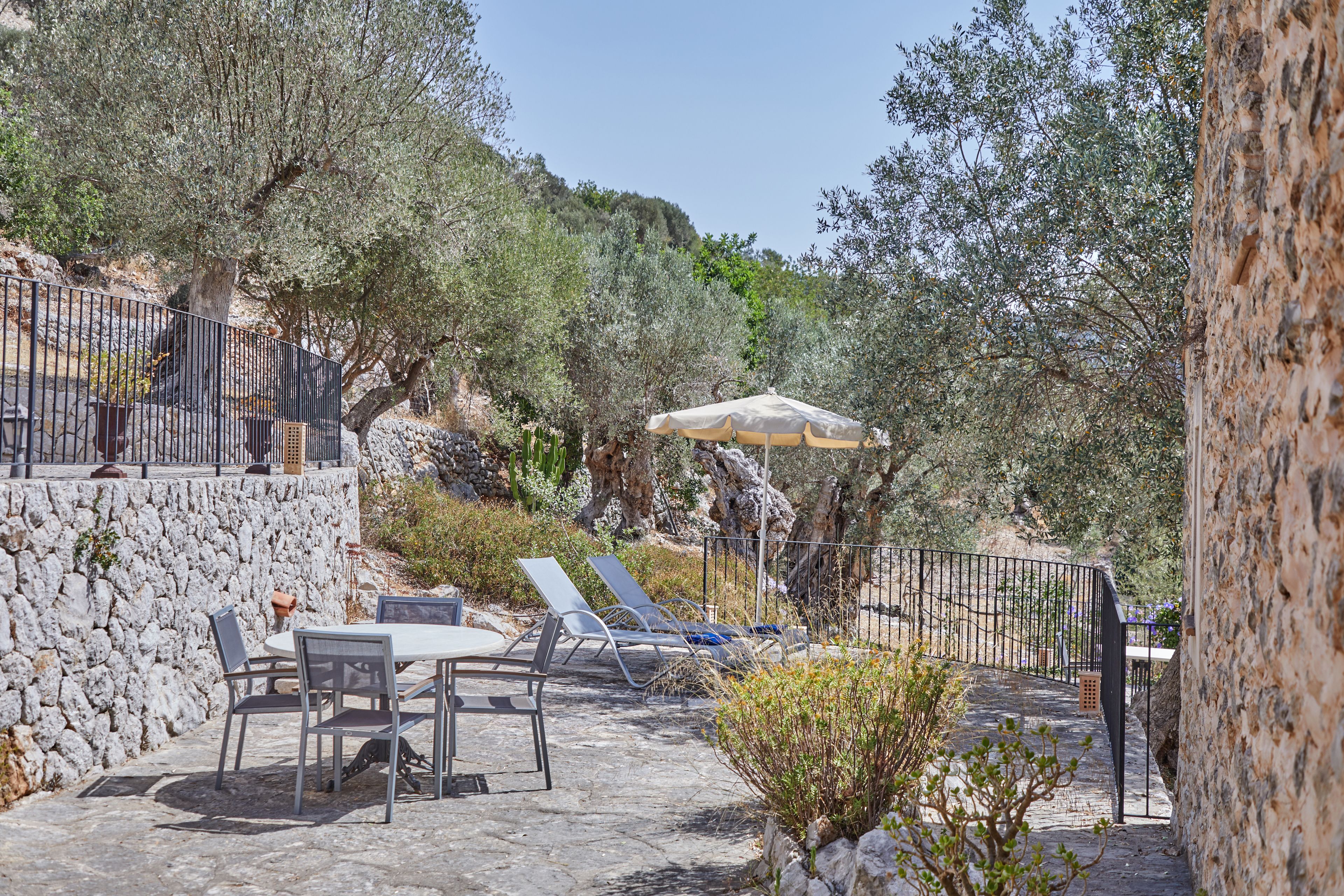An outdoor patio with stone flooring, a table with chairs, and a sun umbrella.