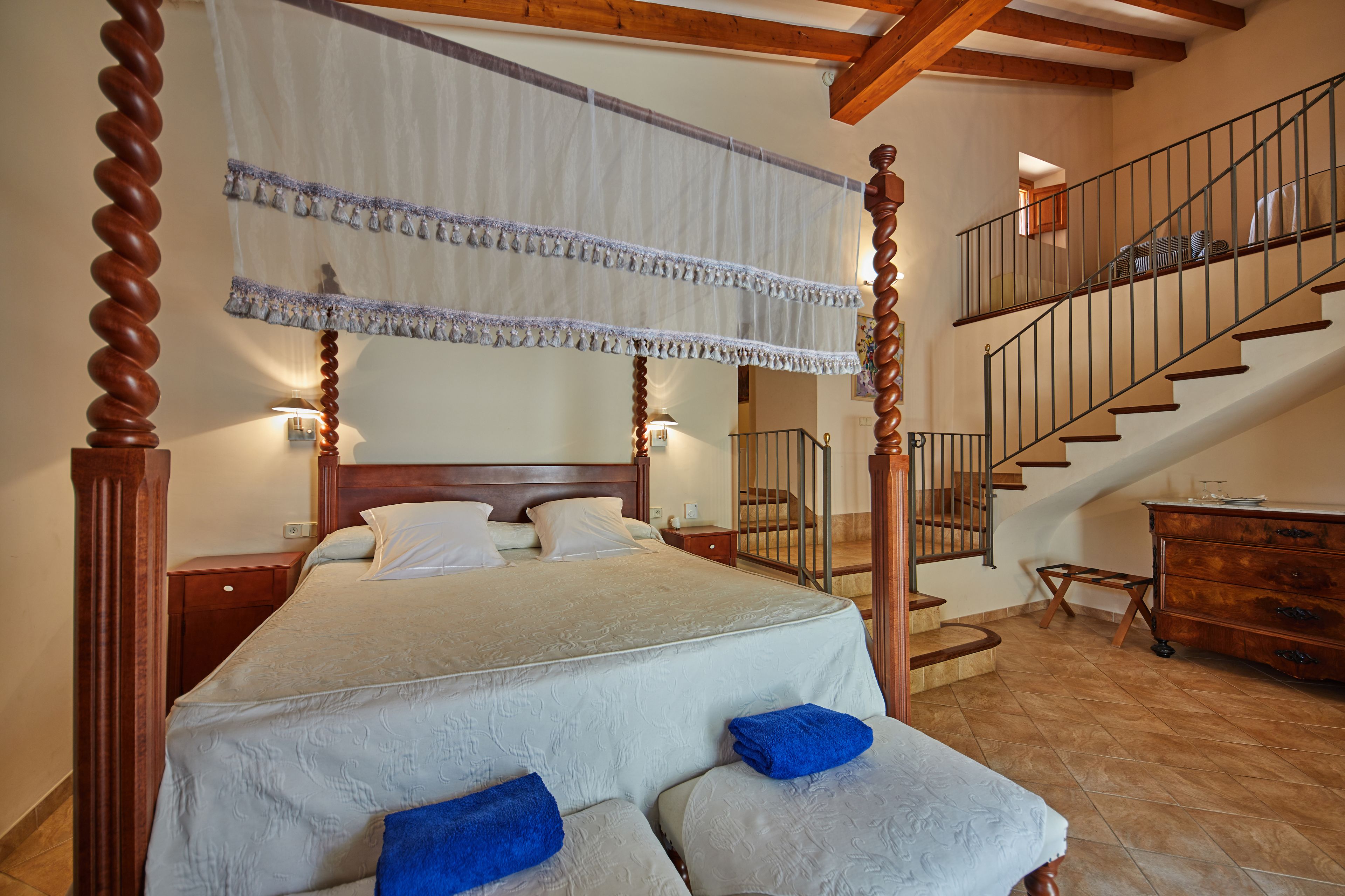 Ein Schlafzimmer mit einem Himmelbett, einer Holztreppe und einer Holzkommode.
