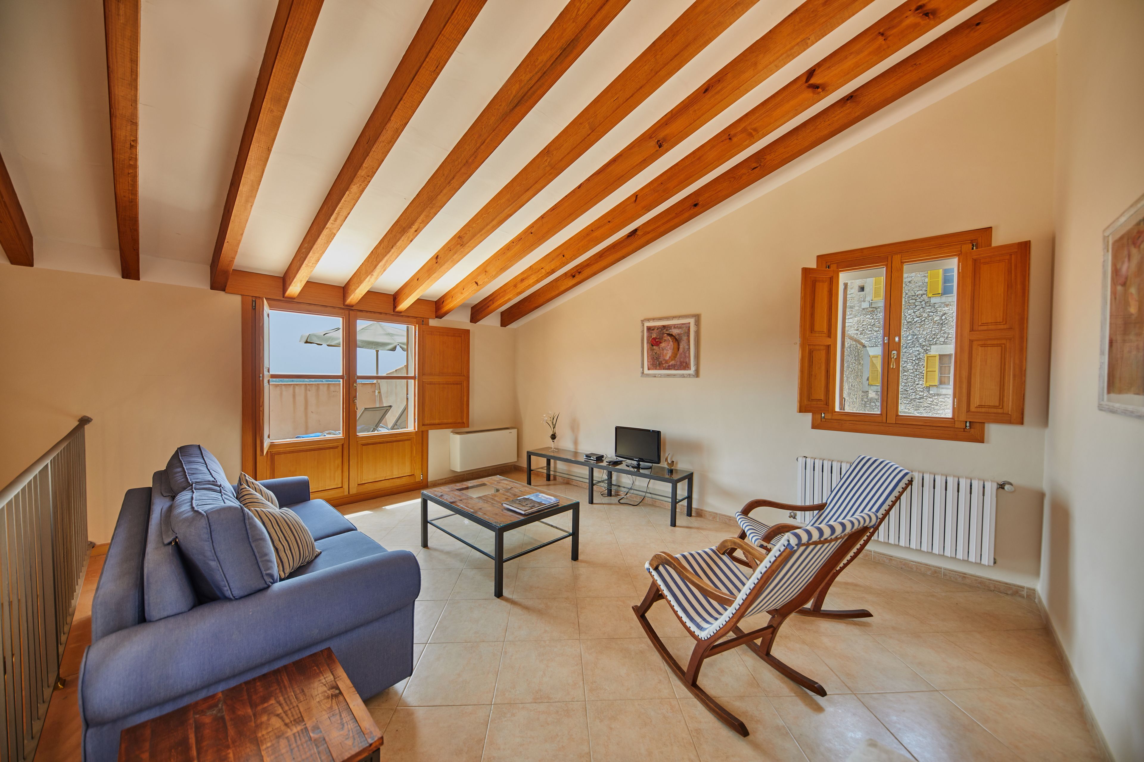 A living room with a sofa, a rocking chair, a coffee table, and a television.