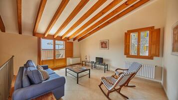 A living room with a sofa, a rocking chair, a coffee table, and a television.