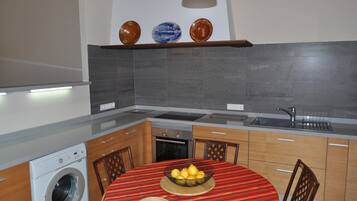 Une cuisine compacte équipée d’un lave-linge, d’un évier et d’un coin repas avec une table dressée pour deux personnes.