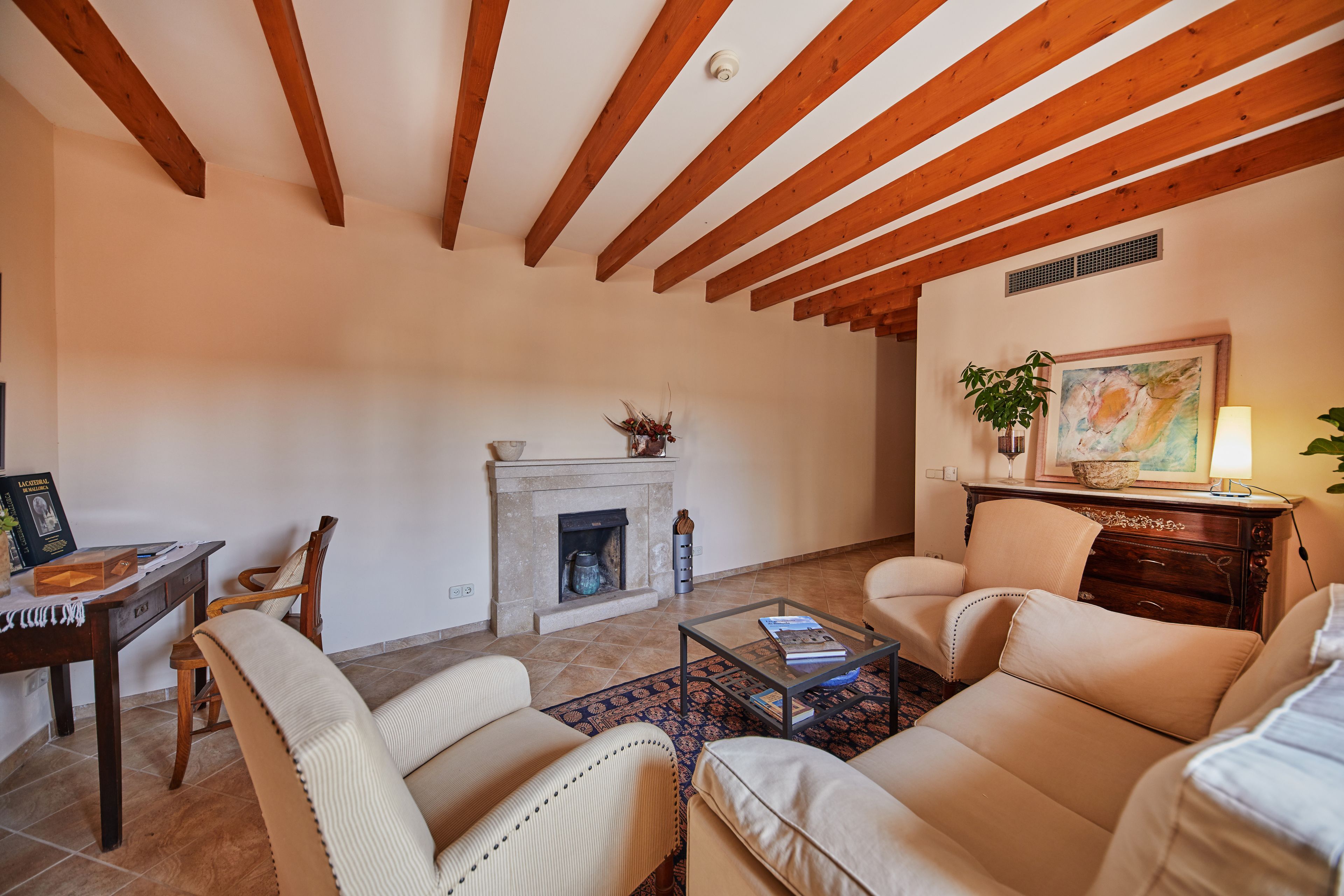 A living room with wooden beams, a fireplace, a sofa, a coffee table, and a lamp.
