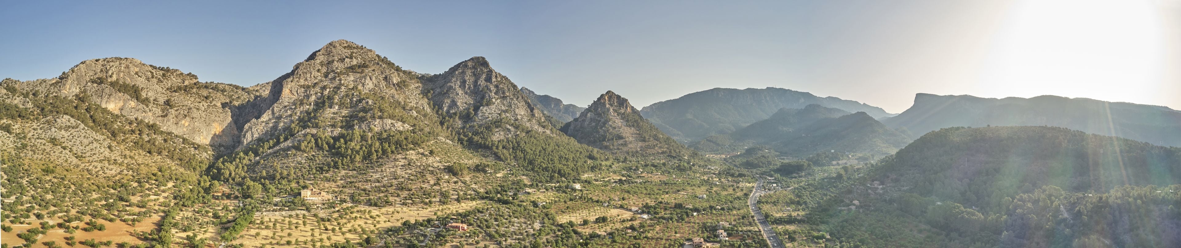 Un paisaje montañoso con un valle y edificios dispersos.
