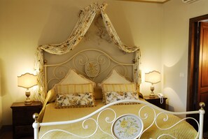 A bed with a canopy, two bedside tables with lamps, and floral-patterned bedding. - Locanda del Molino (Cortona)
