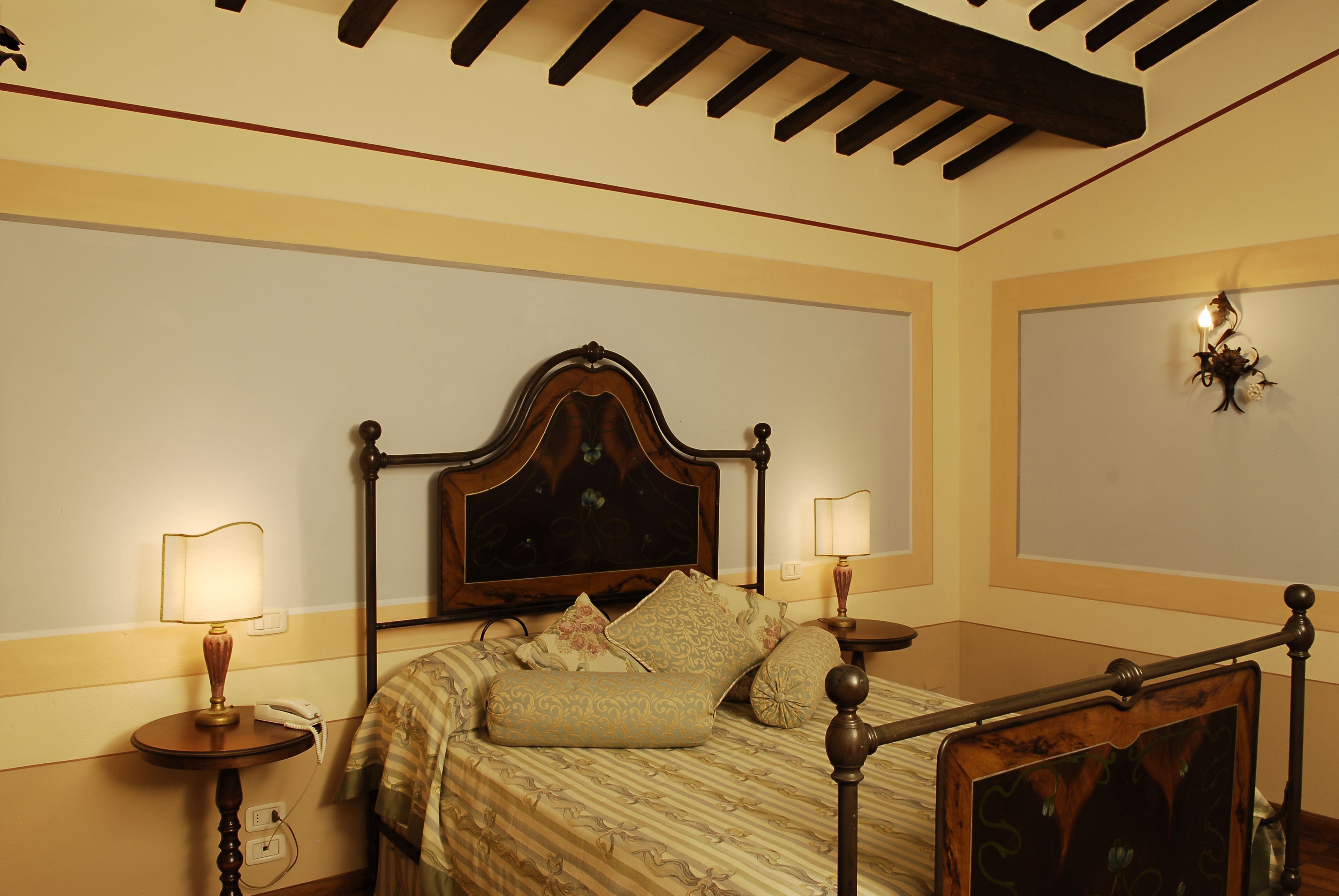 Un dormitorio ordenado con una cama con dosel clásica, dos mesitas de noche y una lámpara de pared.