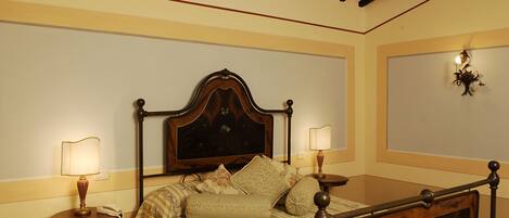 Un dormitorio ordenado con una cama con dosel clásica, dos mesitas de noche y una lámpara de pared.