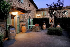 A stone building with a sign reading 'Ocaña del Molino' and a courtyard with wooden barrels and potted plants. - Locanda del Molino (Cortona)