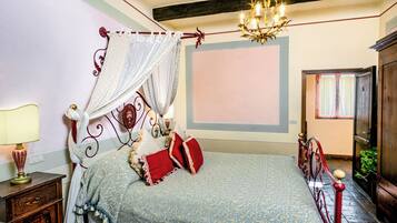 Quarto com uma cama de dossel, um candelabro e uma mesa de cabeceira com abajur.